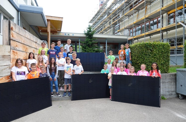 Solarstrom: Die beiden Schulklassen 1 / 2a (rechts) und die Schulklasse 5 nehmen symbolisch die ersten vier Solarpanels vor der Baustelle Schulhaus Rüediswil in Empfang. Foto Roland Meyer