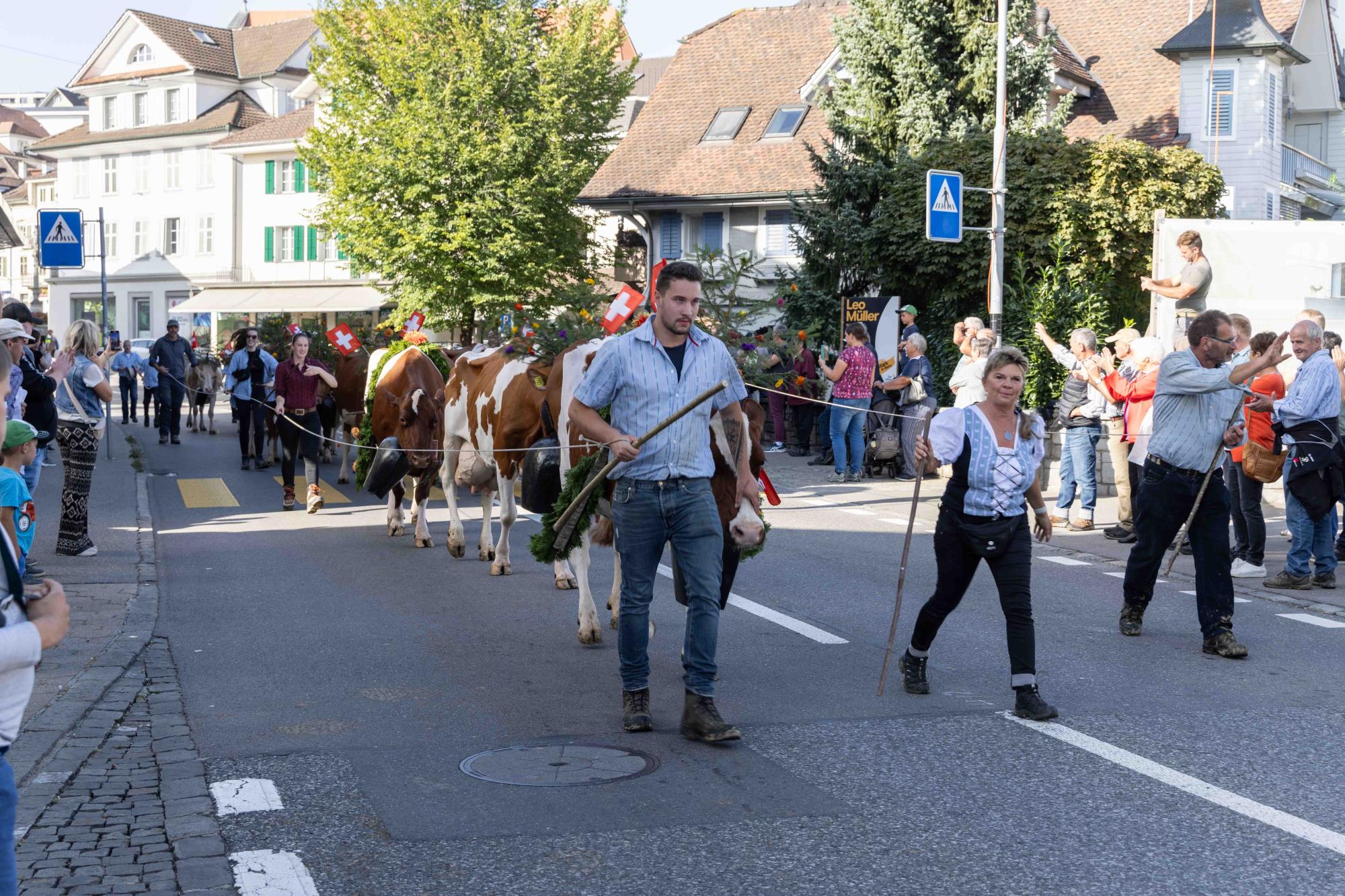 Ein letztes Mal winkte Josef Rölli (rechts) vom Hof Hapfig auf dem Nachhauseweg dem Publikum zu. Die Treiber-Crew mit Sohn Reto Rölli (links) und Evelyne Roduner (Mitte) führt die Kühe sicher durchs Dorf. Foto Ramona Meyer-Stöckli